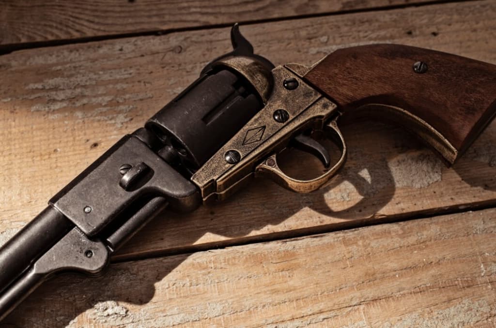 A vintage revolver with a wooden grip rests on aged planks