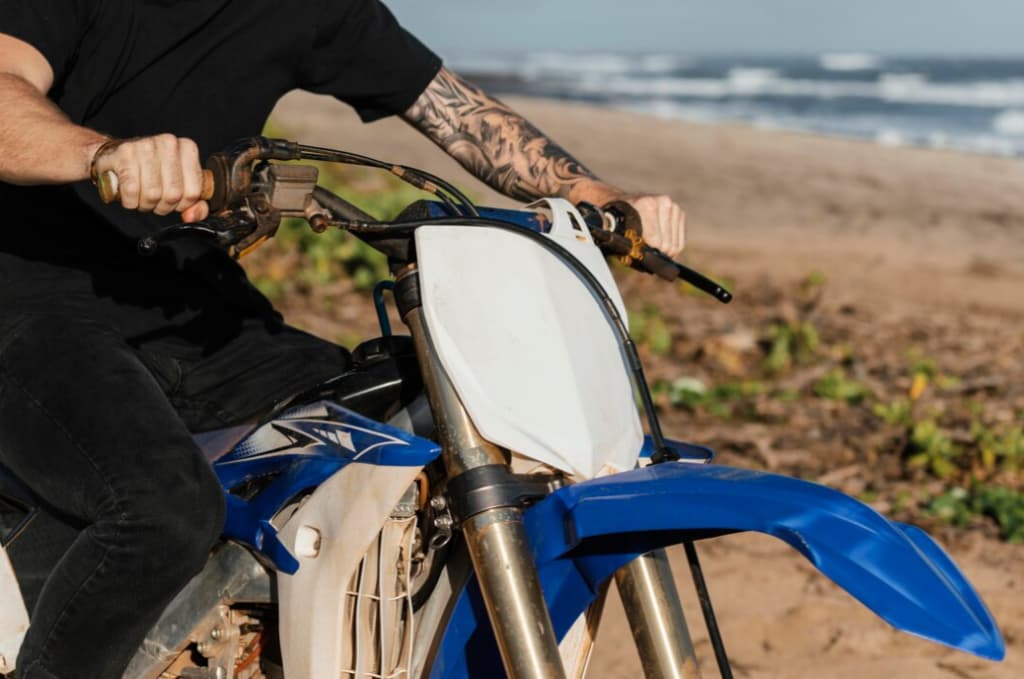 A person riding a blue and white dirt bike on the beach